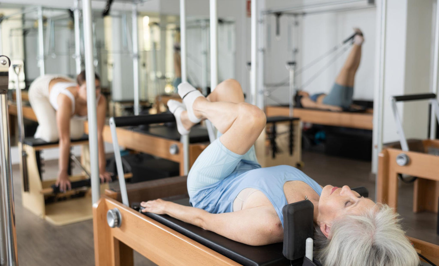 Older woman doing gentle Pilates exercises on a reformer machine to support joint health and reduce arthritis pain