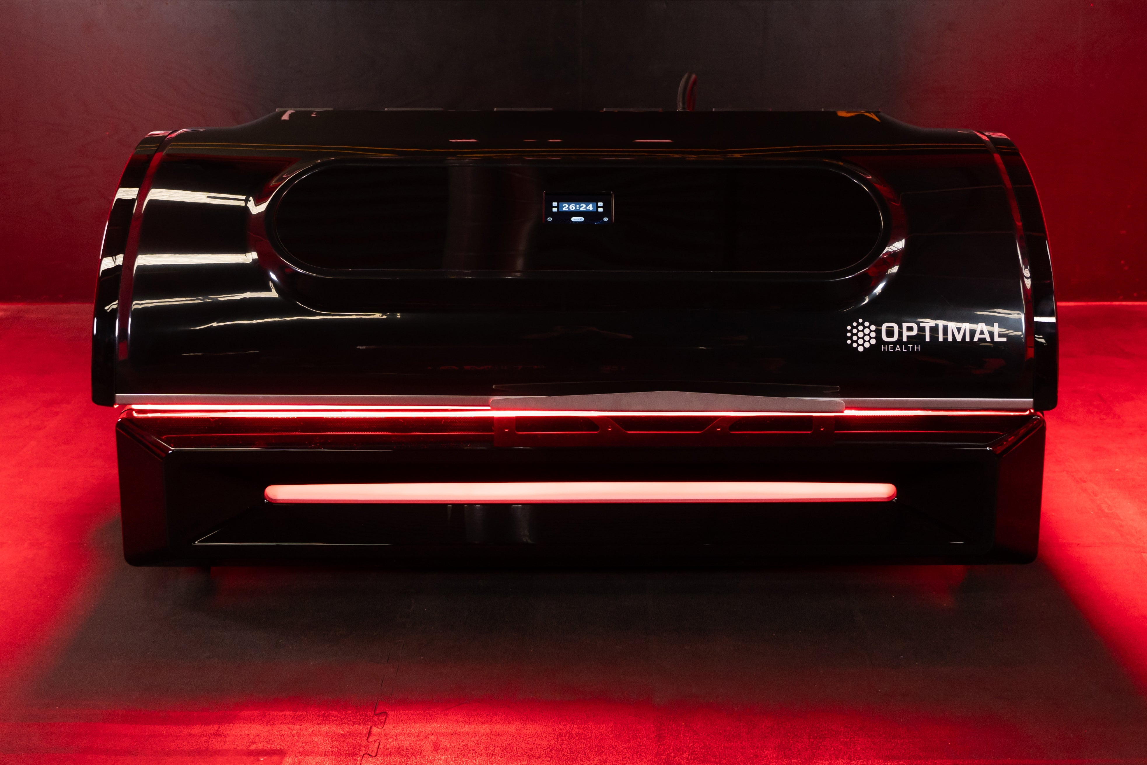 Front view of closed Optimal Health red light therapy bed with digital control screen and illuminated red accents.