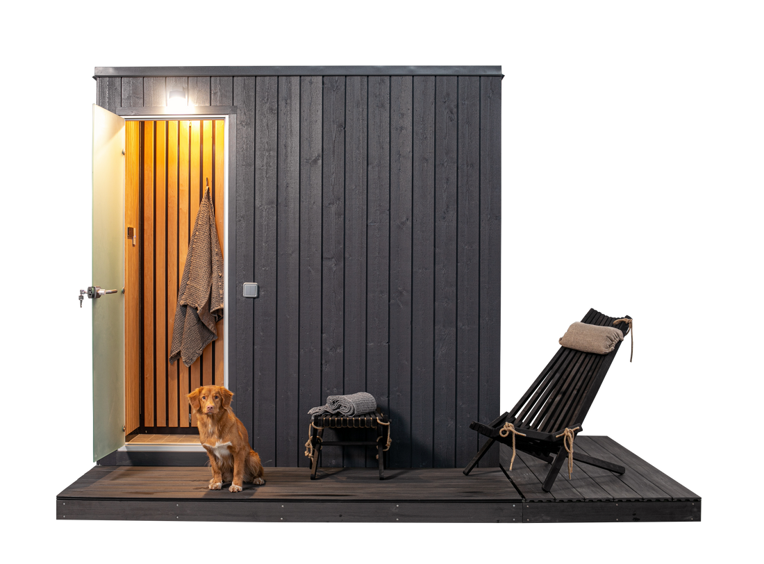 KUUT Outdoor Steam Sauna with open door revealing wood interior, dog sitting on the deck, and lounge chair, on a transparent background.
