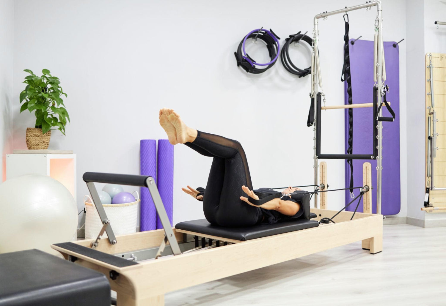 Female doing exercise with straps on Pilates reformer