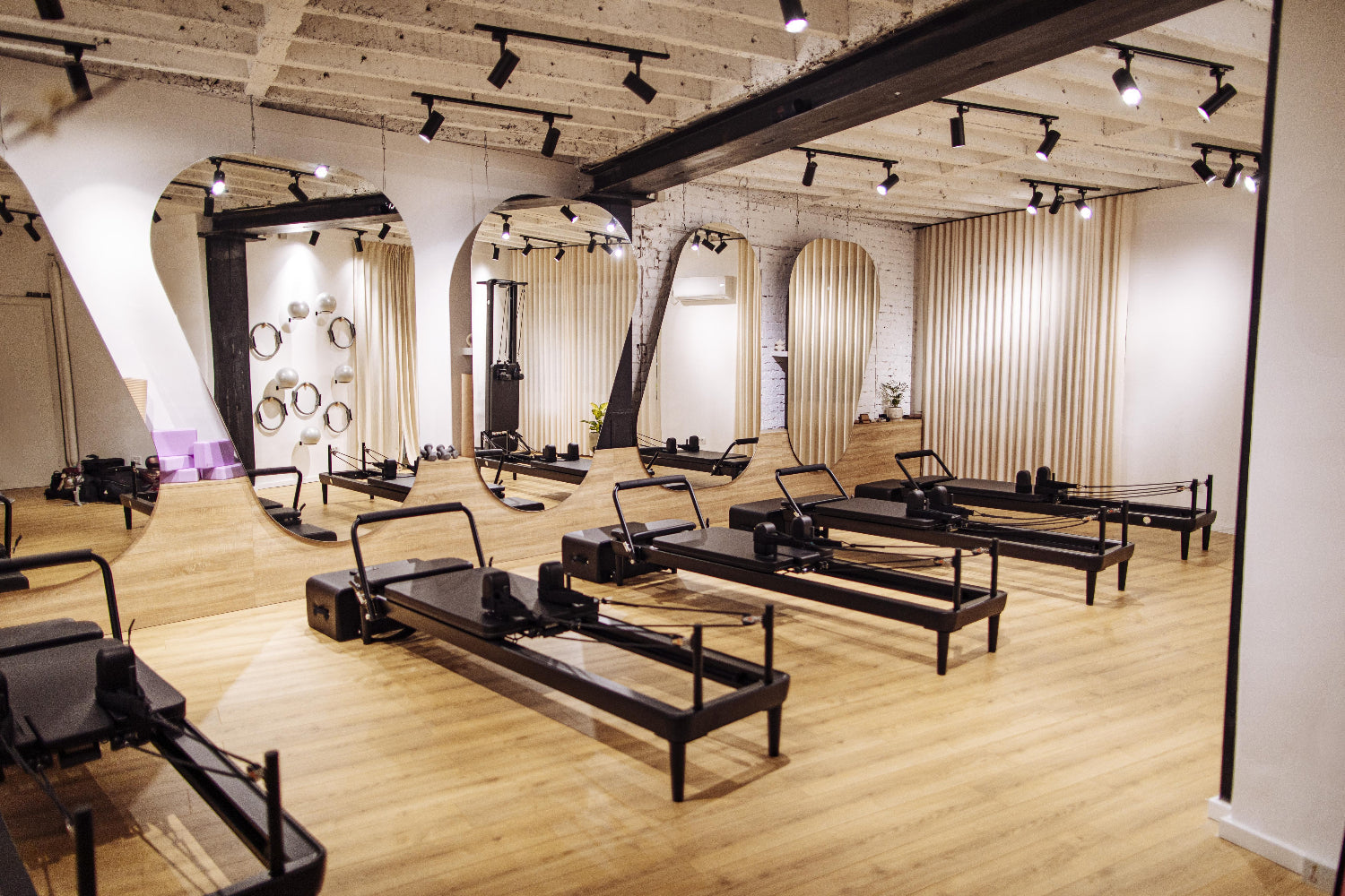 Modern reformer Pilates studio with multiple machines, mirrors, and warm lighting in a boutique fitness space