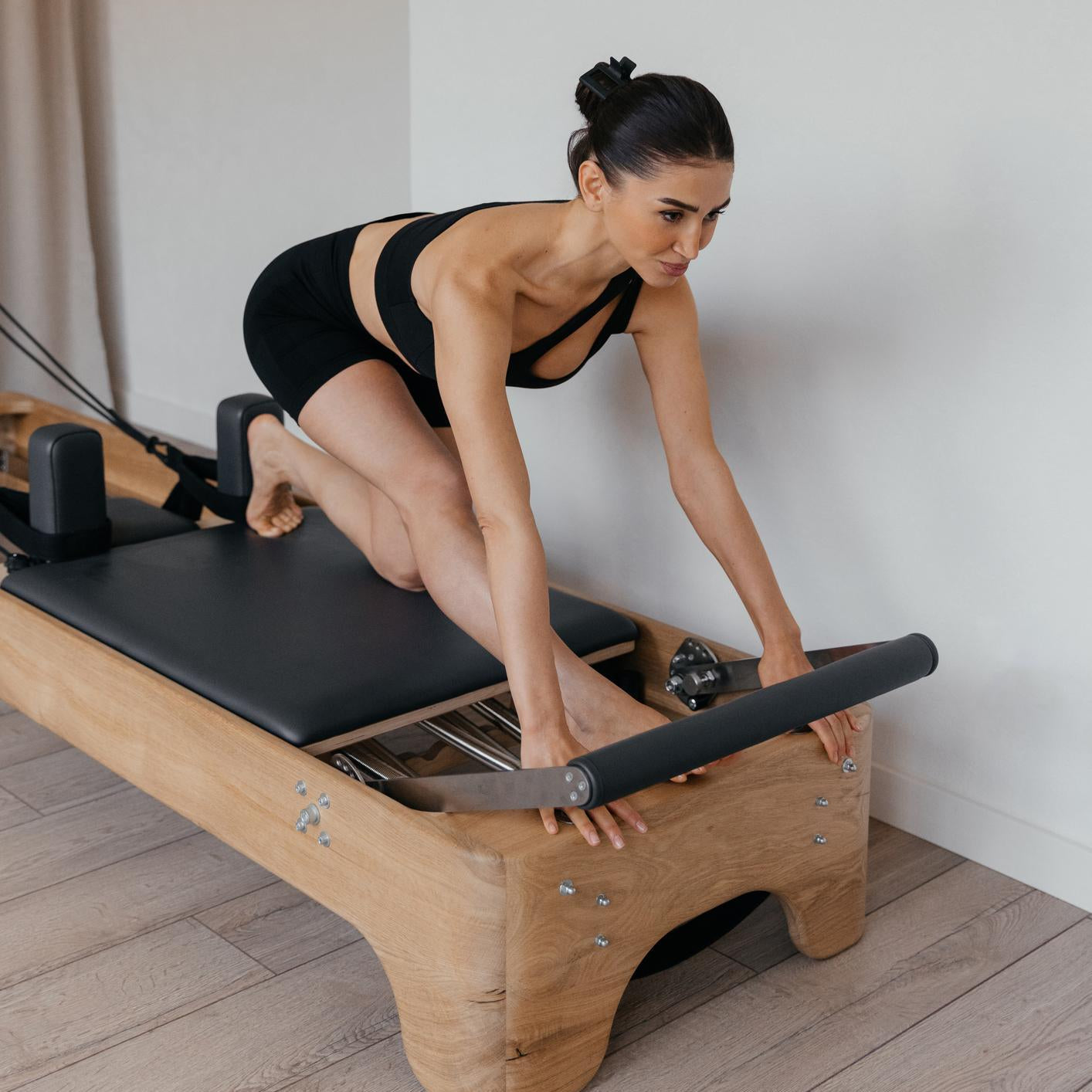 Pilates Reformer Training Machine in studio with athletic models performing exercises that strengthen the entire body. Focus on functional equipment design and full body engagement