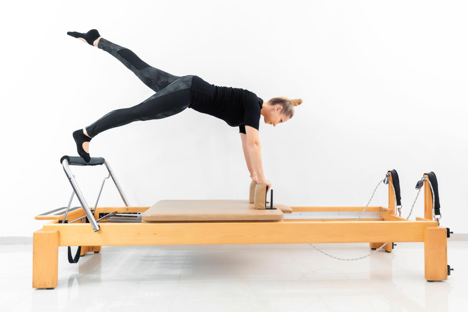 Pilates on reformer machine - a woman does an exercise start variation of Control balance- front