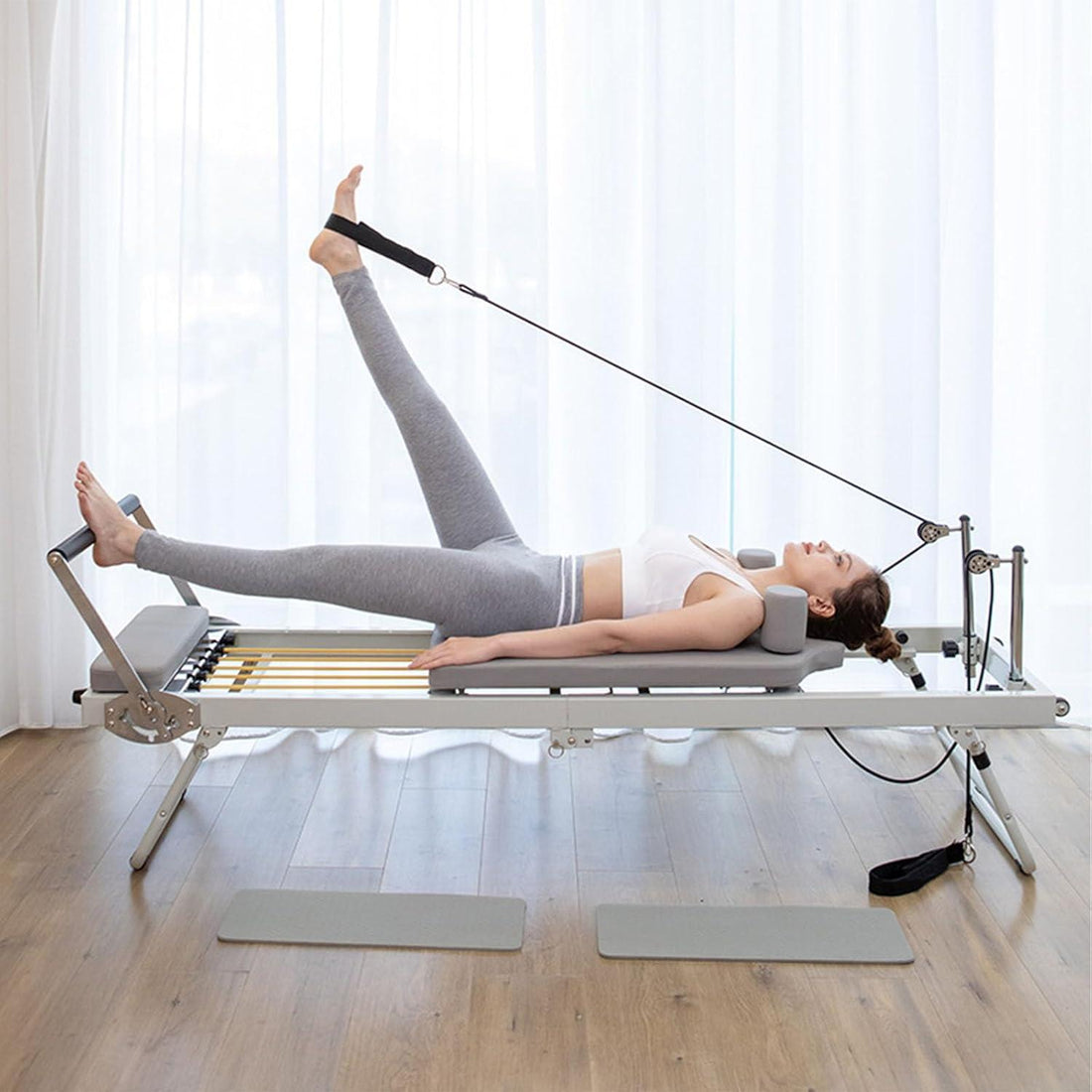 Person using a Pilates reformer machine demonstrating full body extension and carriage length