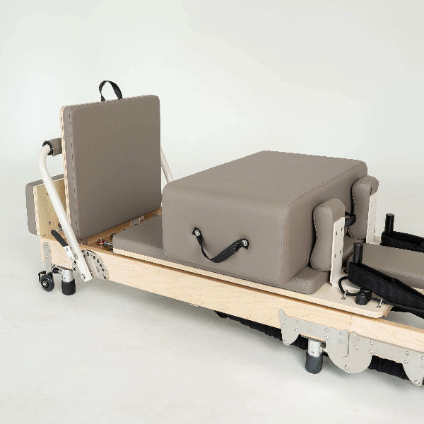 Mocha-colored Pilates reformer with maple frame and box