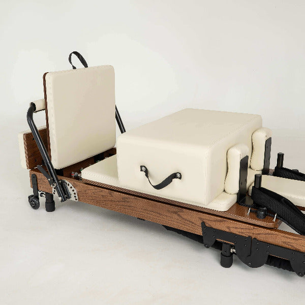 Beige Pilates reformer with red oak wood frame and matching accessories.