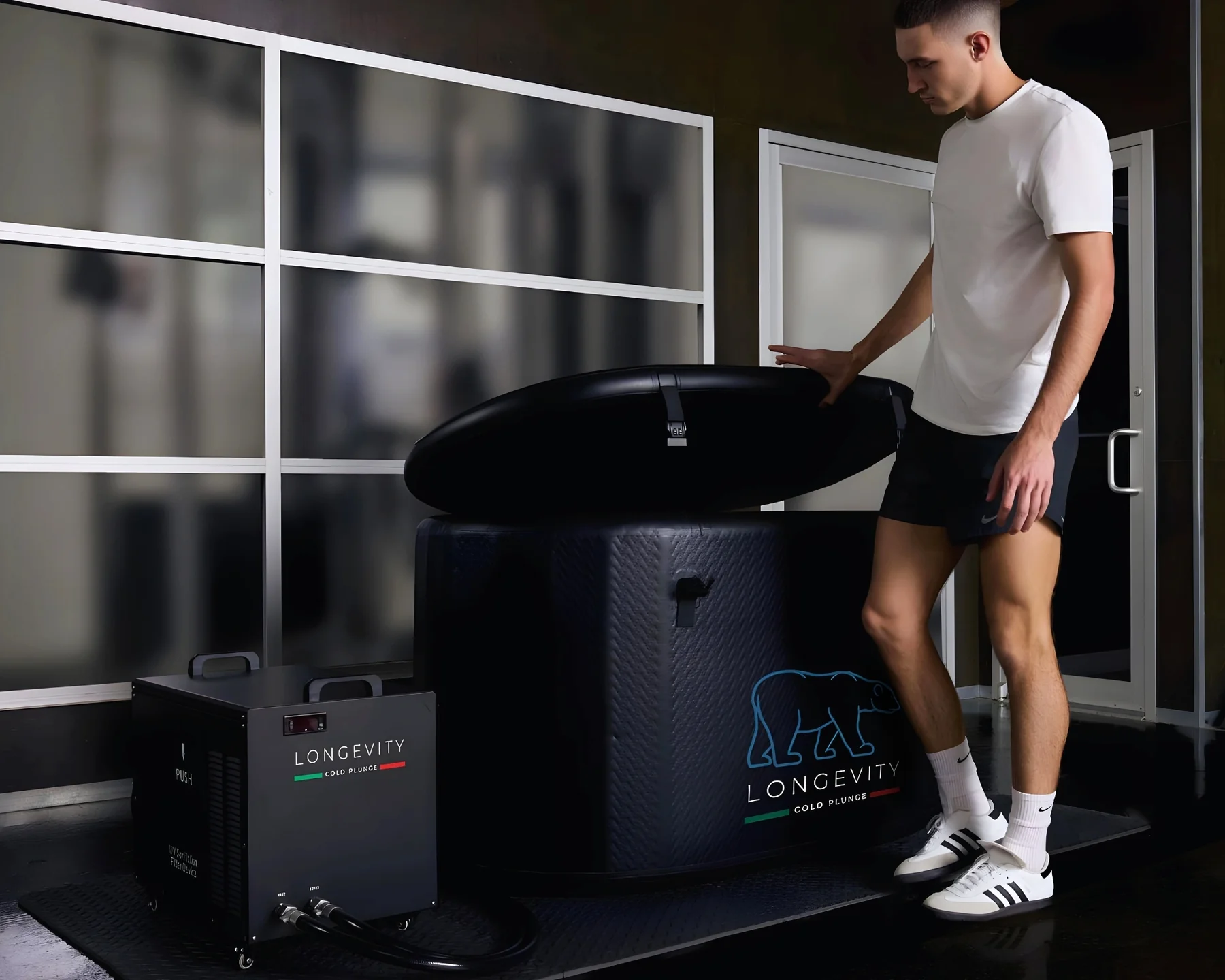Man in athletic wear opening Longevity Cold Plunge lid in a gym environment.