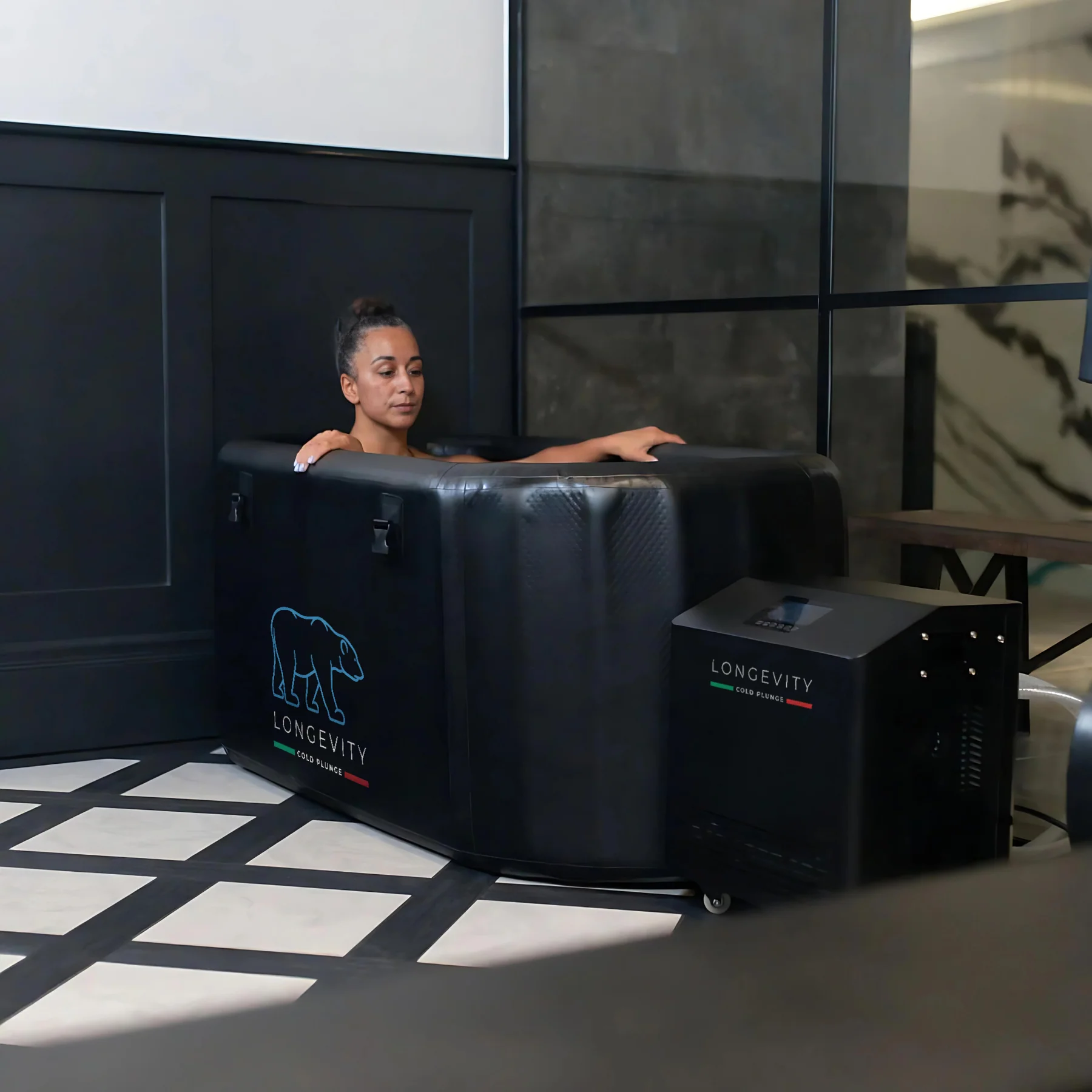 Woman using Longevity Cold Plunge in a modern indoor space with black panelled walls.