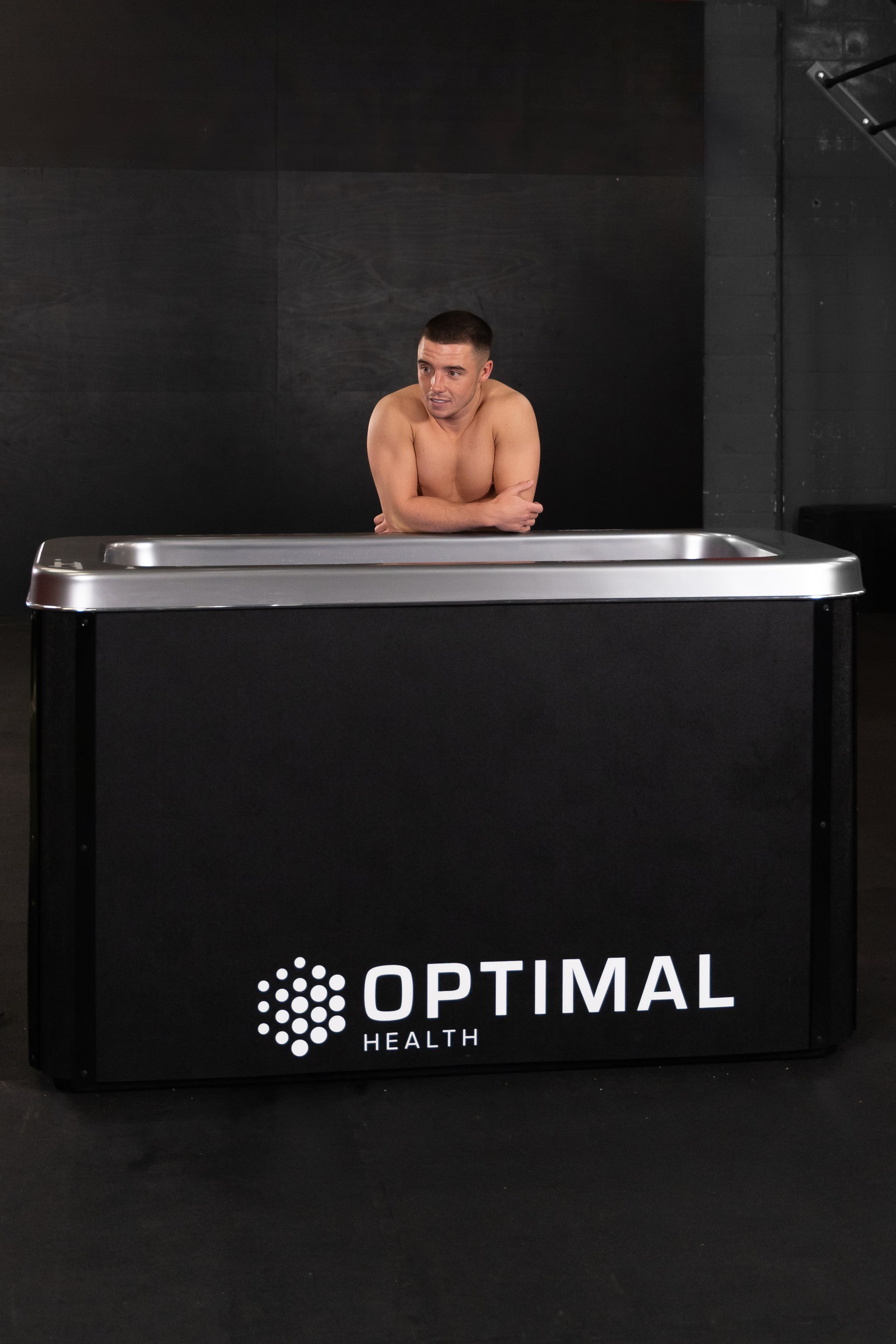 Man resting arms on Optimal Health Ice Bath.