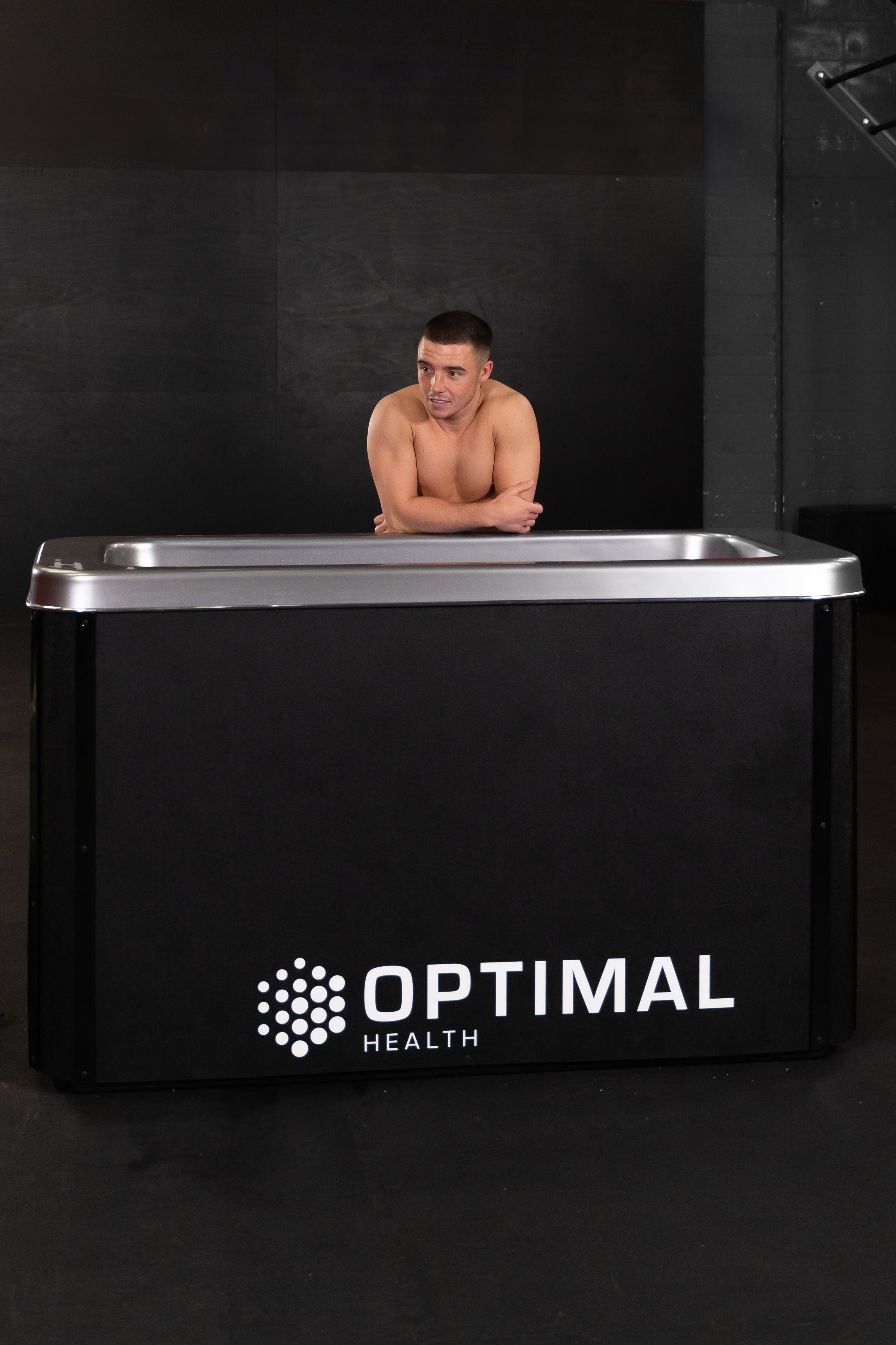 Man resting arms on Optimal Health Ice Bath.