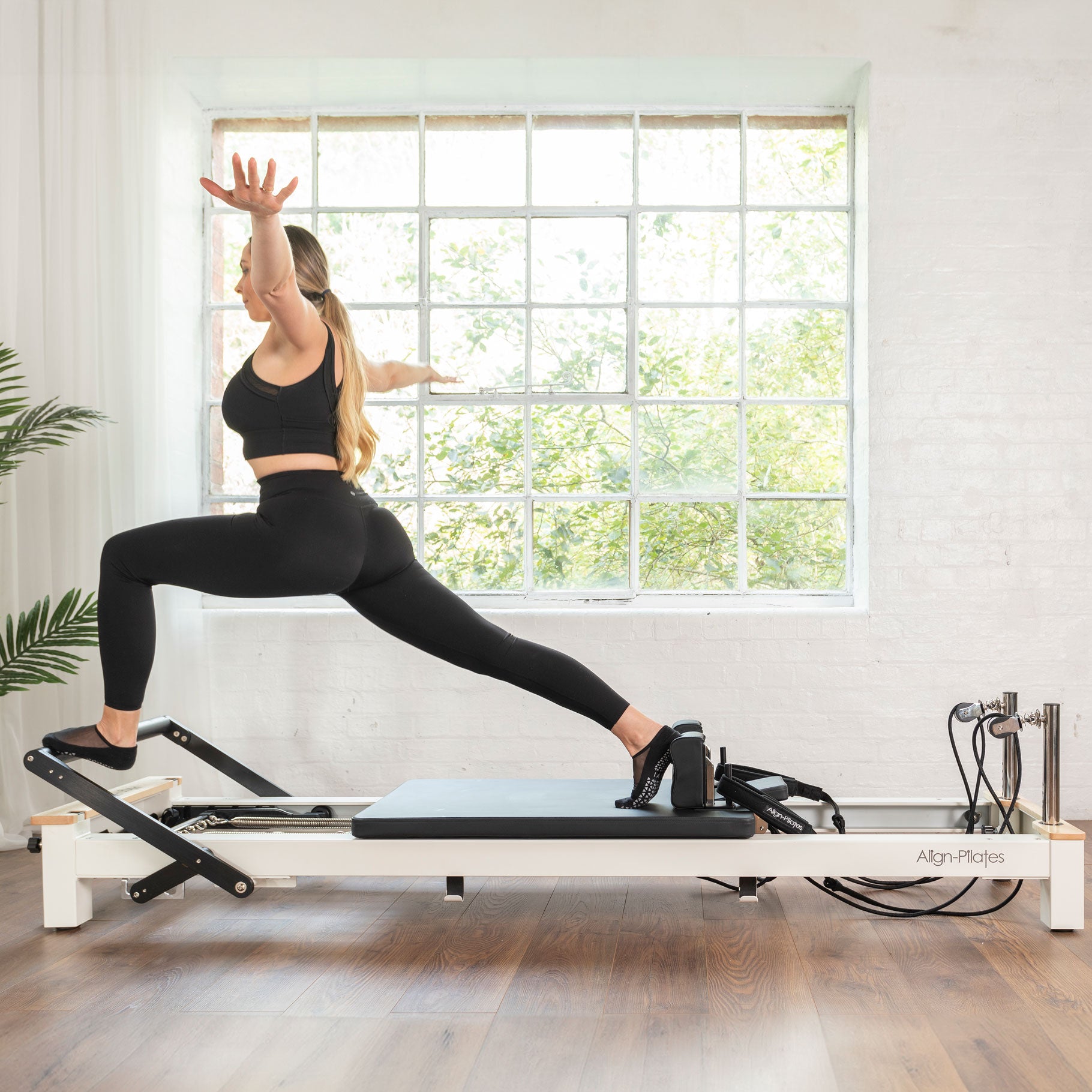 Woman performing an exercise on the Align-Pilates C8-S Pro Pilates reformer