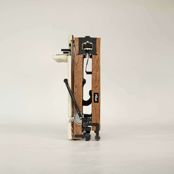 Beige Pilates reformer side view highlighting red oak frame and footbar.