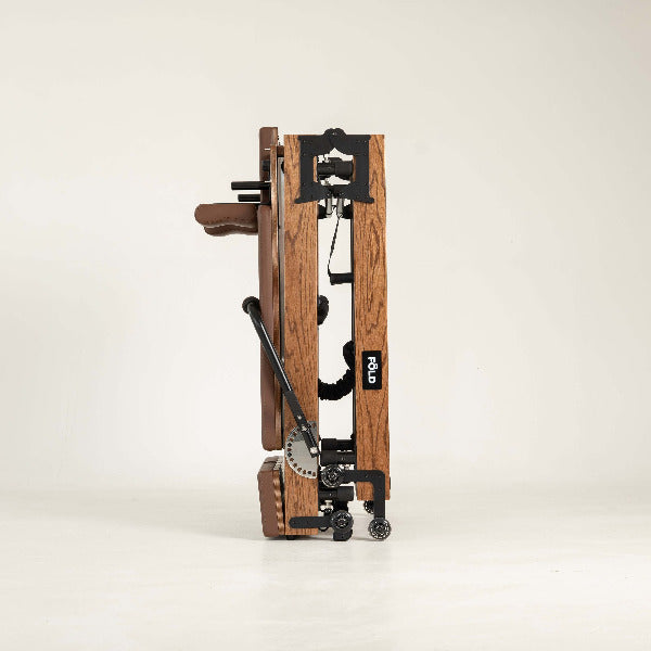 Brown Pilates reformer side profile with red oak frame and adjustable bar.