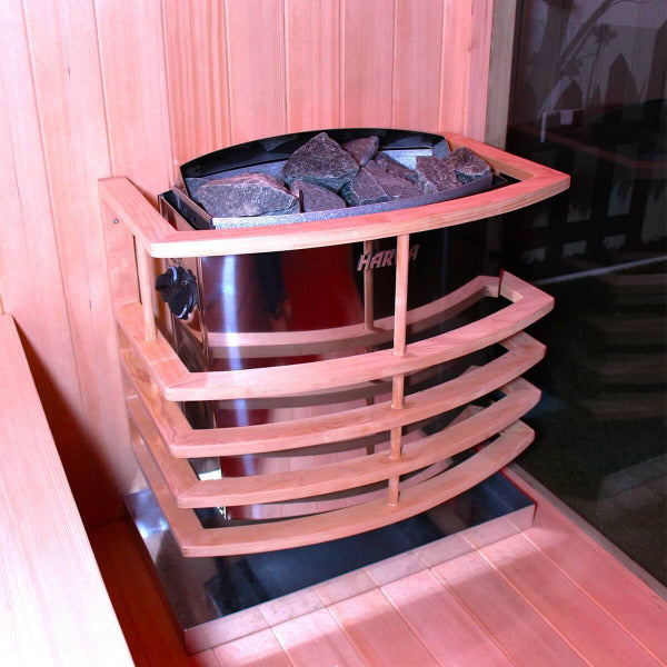 Harvia electric sauna stove filled with sauna stones and surrounded by wooden guard.