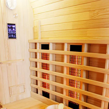 Interior view of the Centura Heat Outdoor Cube Sauna showing wooden bench, bucket and ladle, and glowing infrared heaters, on a light wood background.