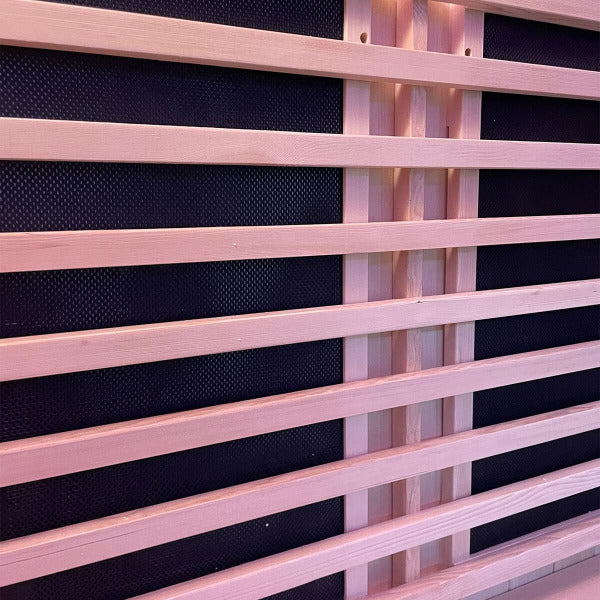 Close-up of infrared heating panels behind protective wooden slats inside sauna.