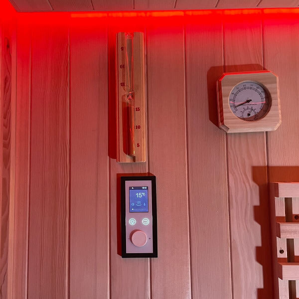 Sauna wall with control panel, sand timer and thermometer under red LED lighting