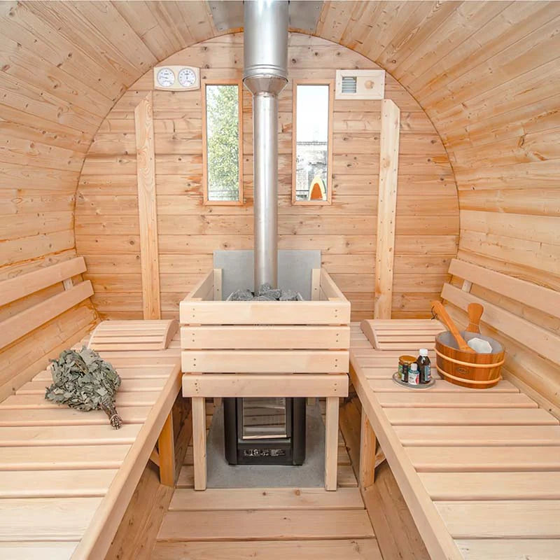Interior of a wooden barrel sauna with benches and a central wood stove heater.