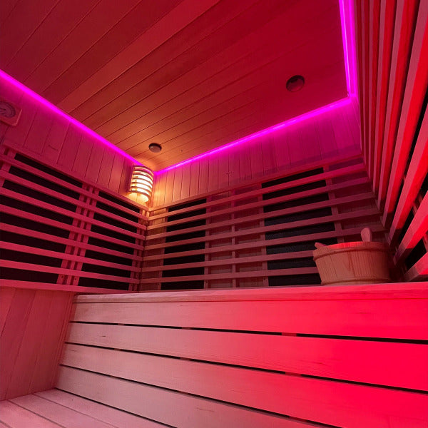 Sauna interior illuminated with pink chromatherapy lighting and wooden bench seating